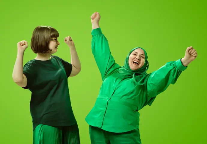 Two people dressed in green celebrating with their arms in the air excited