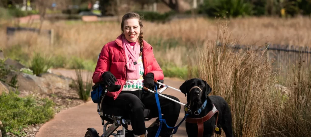 Women in wheelchair with her guide dog in their harness