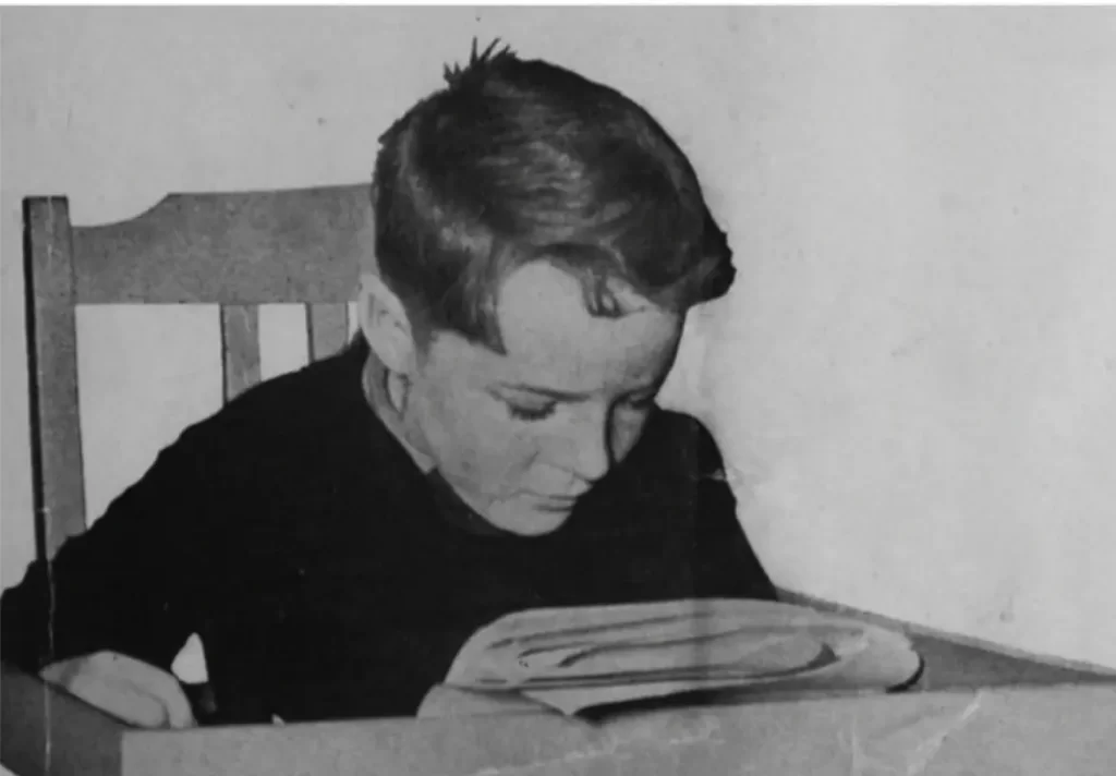 Old image of boy reading the newspaper at a table