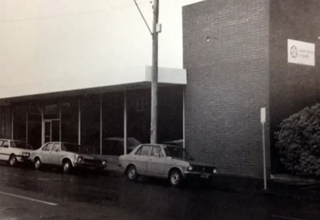 Image of old building with old cars parked along the street