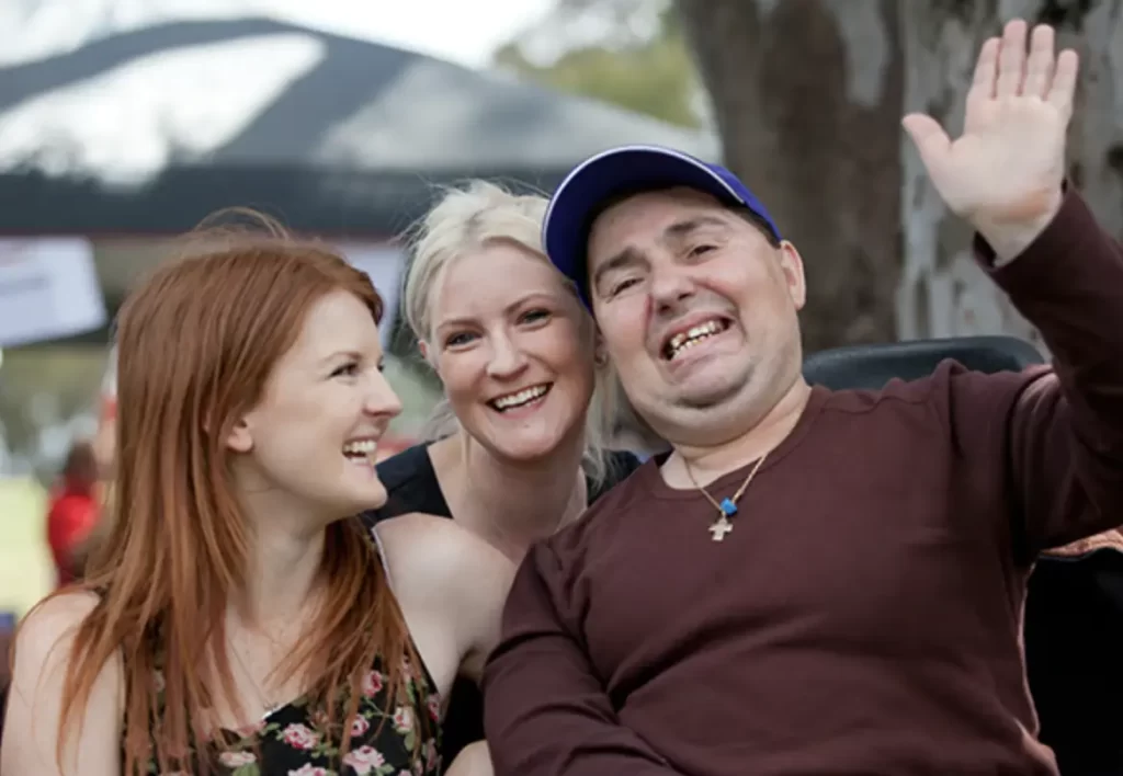 Three people smiling and waving at the camera