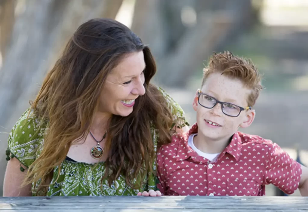 A woman and a younger boy smiling sitting at a table