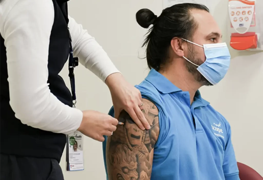 Man in a mask receiving an injection