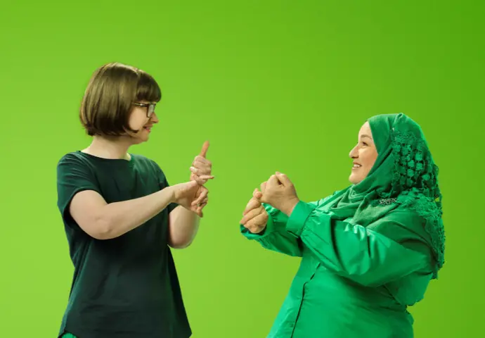 Two people dressed in green celebrating with their arms in the air excited