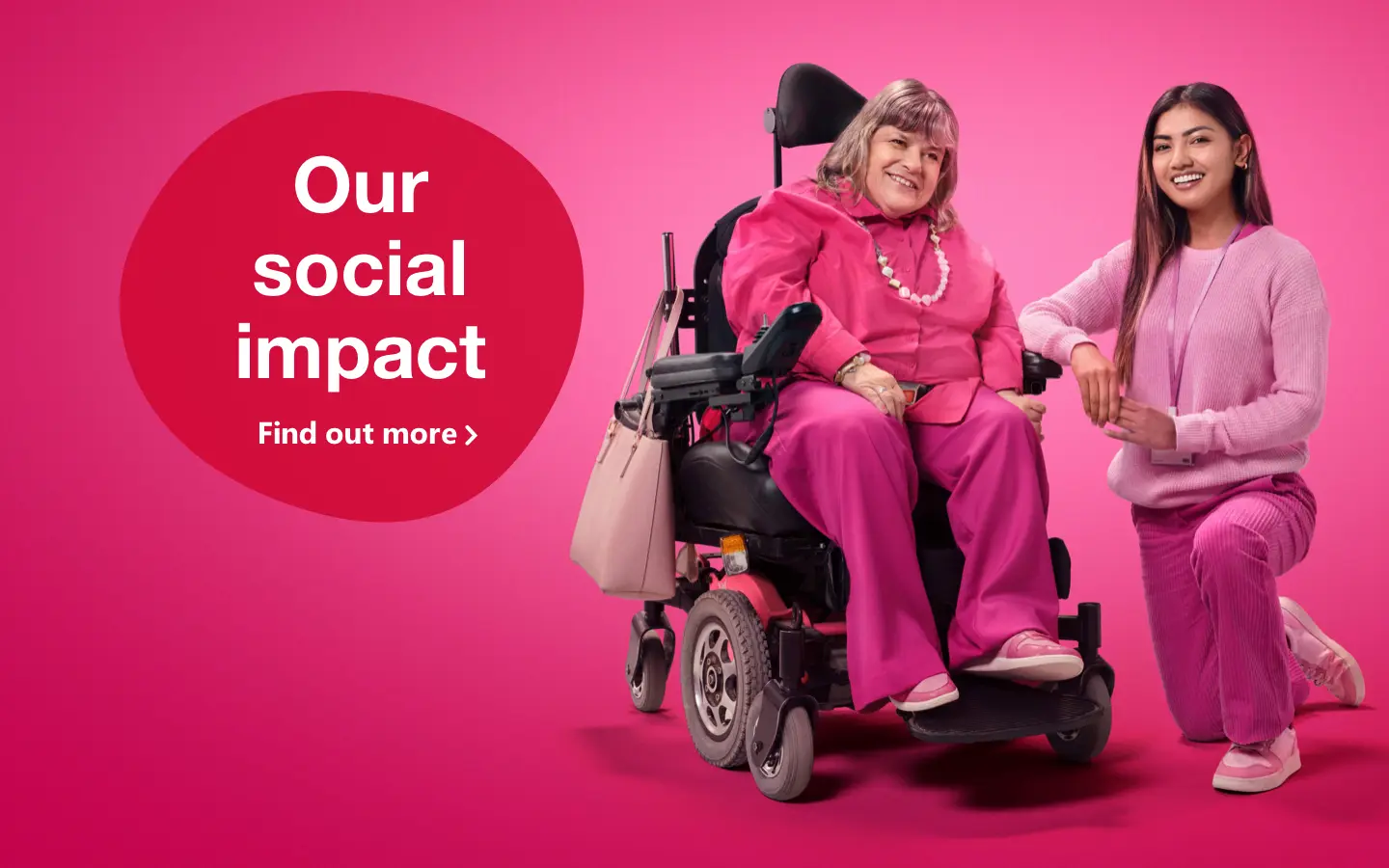 Two women dressed in pink staring at each other smiling, one is in a wheelchair