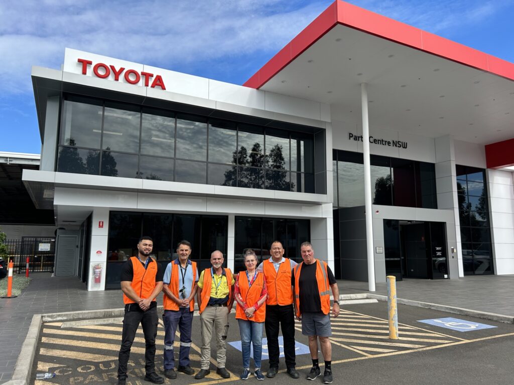 The staff at Toyota standing out the front of their building in high-vis vests