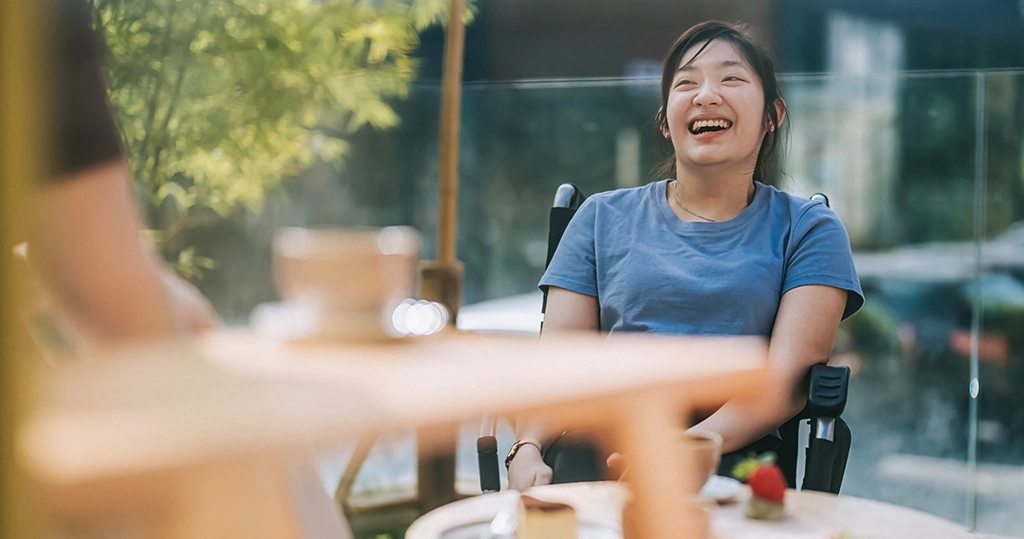 Woman in a wheelchair sitting talking to a friend having coffee